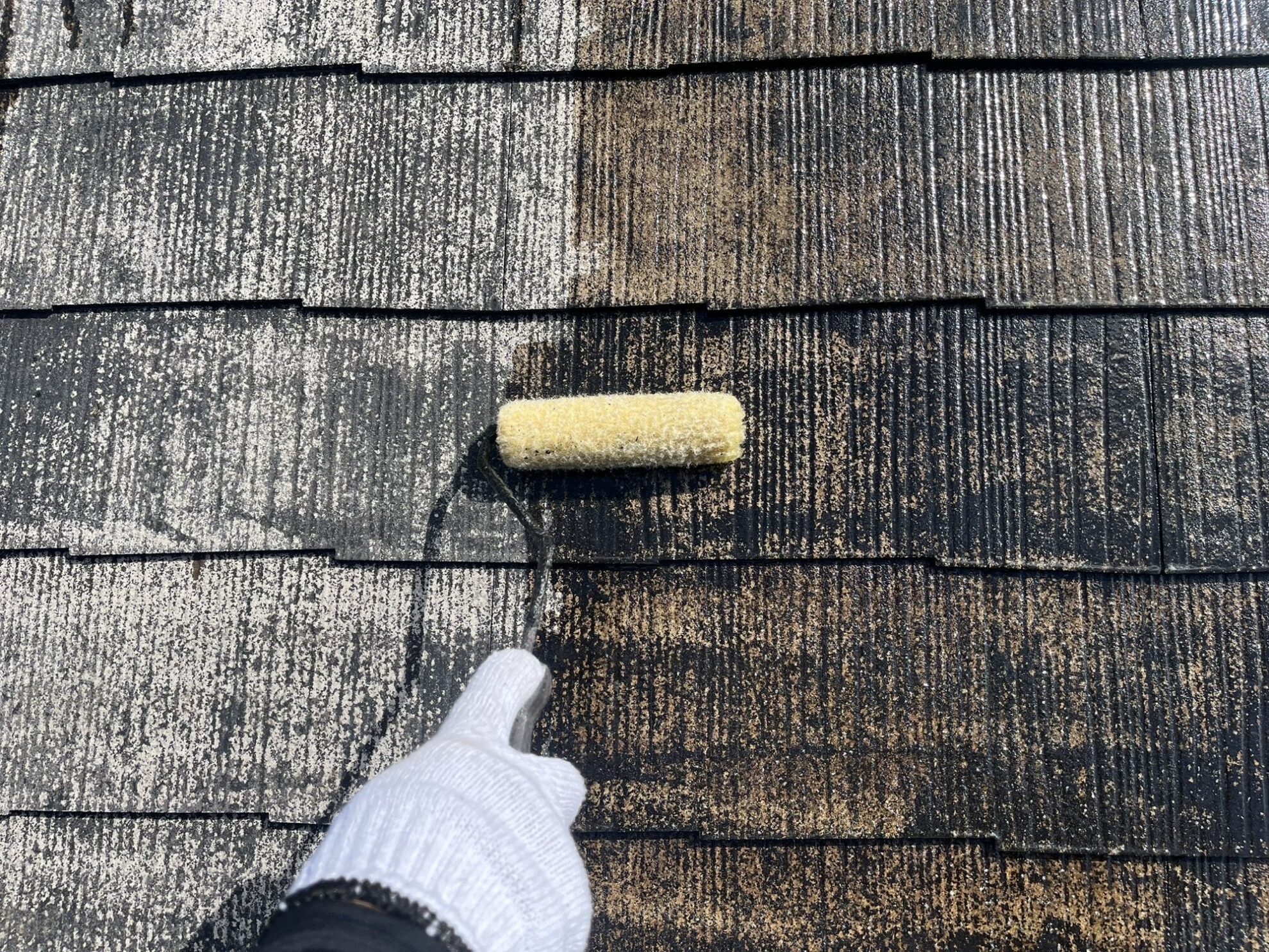 宮城県多賀城市のスレート屋根に下塗り塗装を行っている様子。ローラーで真っ白になった部分と劣化した部分の違いがはっきり見えます。