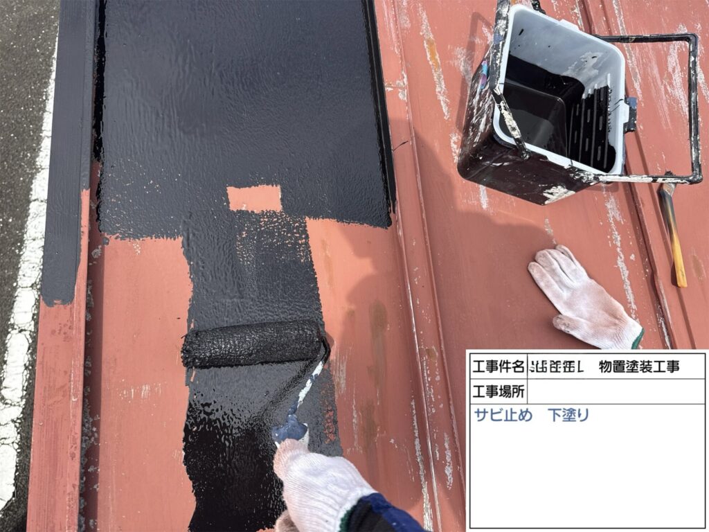 塩竈市の物置金属屋根に錆止め塗料をローラーで下塗りしている様子
